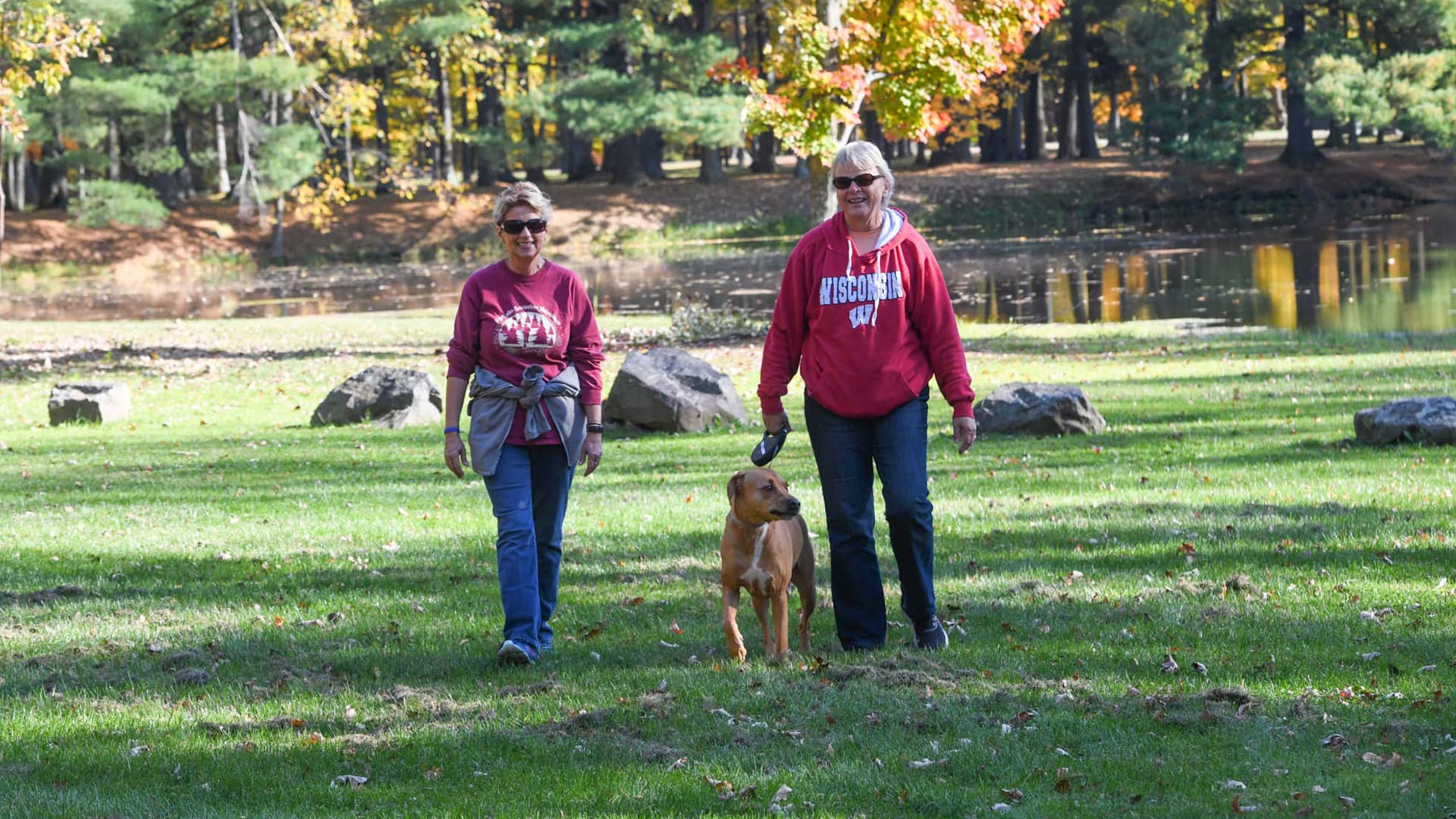 Pet-friendly hotels, restaurants & more in central Wisconsin | Two women walking a dog in fall at North Wood County Park near Marshfield Wisconsin