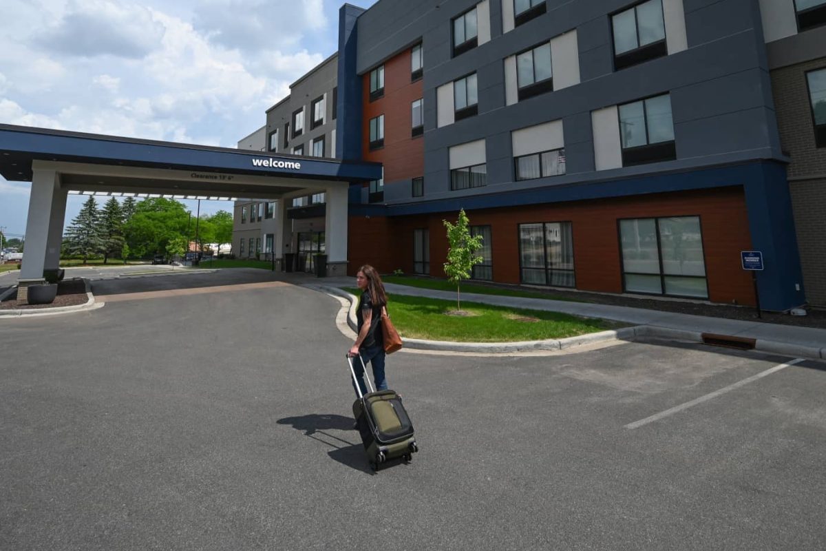 Woman with rolling suitcase outside Hampton Inn & Suites in Marshfield Wisconsin