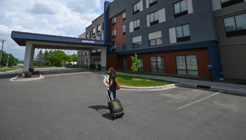 Woman with rolling suitcase outside Hampton Inn & Suites in Marshfield Wisconsin